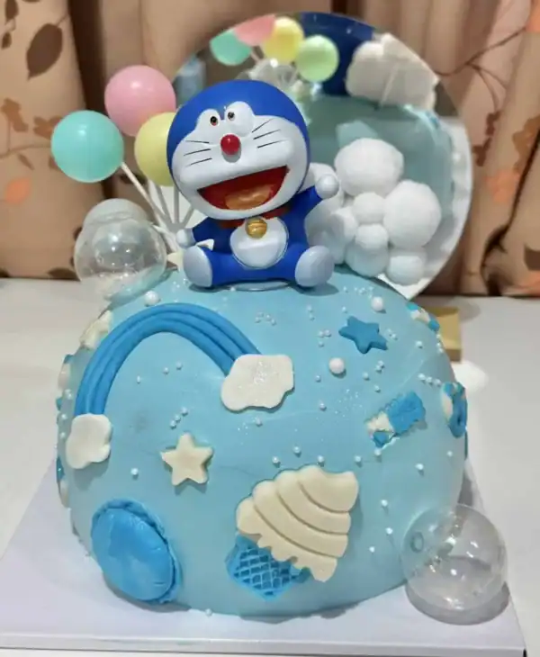 เค้กวันเกิดการ์ตูนโดราเอม่อนสีฟ้าสำหรับทำขนมปังที่บ้าน งานฝีมือเบเกอรี่สดใสเหมาะสำหรับปาร์ตี้เด็กและครอบครัว เน้นการตกแต่งธีมสีฟ้าพร้อมตัวละครโดราเอมอนและองค์ประกอบลูกโป่งและขนมหวานต่าง ๆ เพิ่มความน่ารักและความสนุกสนานในโอกาสพิเศษ.