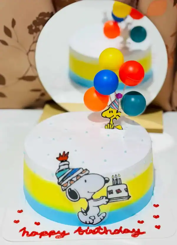 เค้กวันเกิด Snoopy และเพื่อน ๆ พร้อมลูกโป่งสีสันสดใส สำหรับฉลองโอกาสพิเศษด้วยภาพถ่ายอาหารและขนมหวาน.