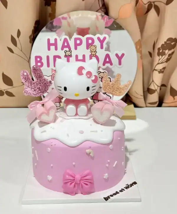 ของหวานวันเกิดเค้กน่ารักธีม Hello Kitty สำหรับเด็กผู้หญิง พร้อมเทียนและตกแต่งด้วยขนมหวานสีชมพูสดใส.