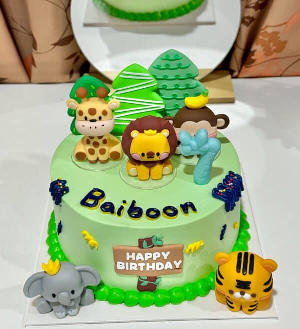 เทียนวันเกิดลายสัตว์น่ารักบนเค้กสีเขียวในธีมป่าไม้ พร้อมข้อความ "HAPPY BIRTHDAY" สำหรับเฉลิมฉลองวันเกิดเด็กในบรรยากาศสนุกสนานและน่ารัก.