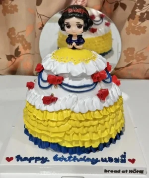 เค้กสโนไวท์หวานละมุนตกแต่งด้วยครีมและลูกกวาดสีสดใส เหมาะสำหรับงานฉลองวันเกิดและโอกาสพิเศษ.