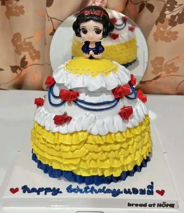 เค้กสโนไวท์หวานละมุนตกแต่งด้วยครีมและลูกกวาดสีสดใส เหมาะสำหรับงานฉลองวันเกิดและโอกาสพิเศษ.