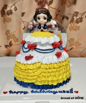 เค้กสโนไวท์หวานละมุนตกแต่งด้วยครีมและลูกกวาดสีสดใส พร้อมตัวตุ๊กตาน่ารักบนยอดเค้ก เหมาะสำหรับงานฉลองและวันเกิดที่ต้องการความน่ารักและความหวาน.