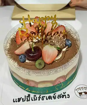 เค้กวันเกิดผลไม้ช็อกโกแลตหวานอร่อย ตกแต่งด้วยผลไม้สดและช็อกโกแลต พร้อมคำว่า Happy Birthday บนยอดเค้ก.