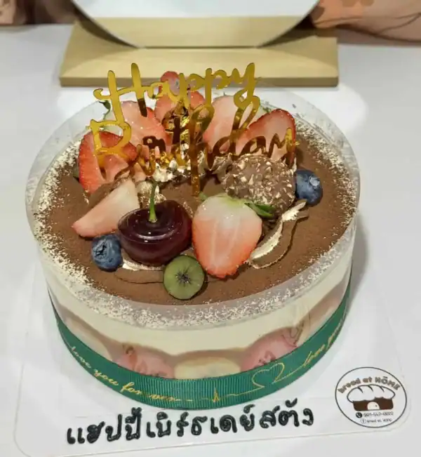 เค้กวันเกิดผลไม้ช็อกโกแลตหวานอร่อย ตกแต่งด้วยผลไม้สดและช็อกโกแลต พร้อมคำว่า Happy Birthday บนยอดเค้ก.